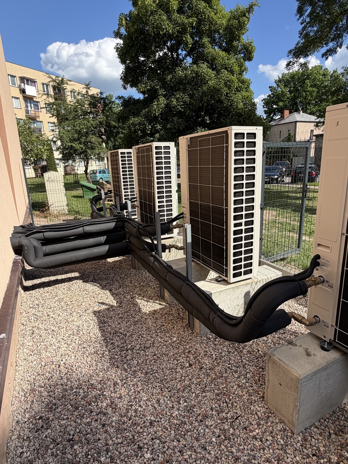 Jednostki zewnętrzne pomp ciepła przy budynku wielorodzinnym – instalacja GMK Instalacje